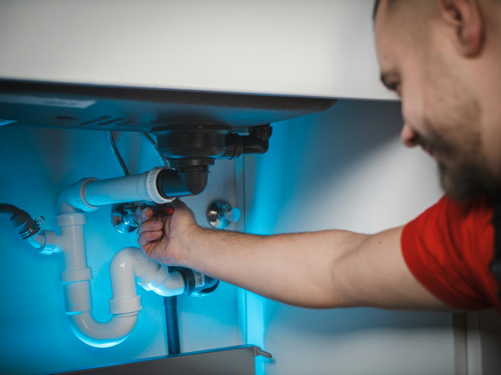 Tècnic reparant una instal·lació de lampisteria sota un lavabo